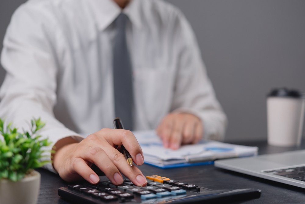 Hand,using,calculator,while,reviewing,financial,documents,,evoking,focus,and